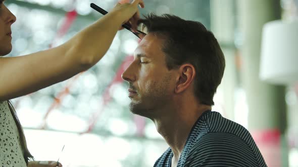 Makeup artist putting makeup on male models face