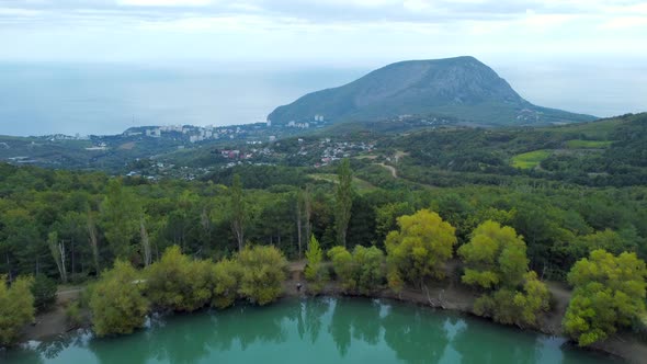 Aerial footage over a green lake with a beautiful sleeping bear mountain at the shore of the sea