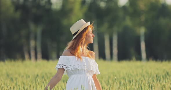 Beautiful Young Woman with a Hat is Walking Across the Field She is Happy alt