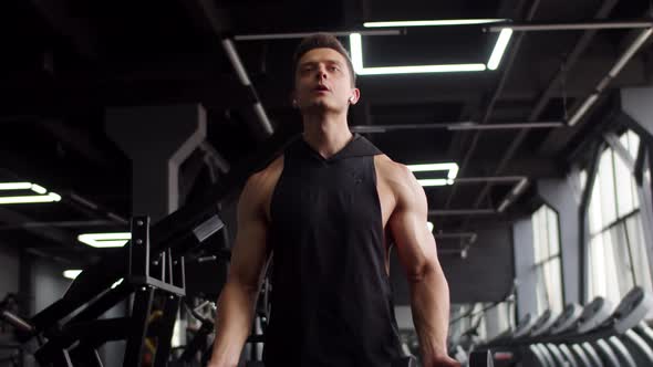 Young Muscular Man Trains in Gym Lifting Dumbbells with Two Hands Front View alt