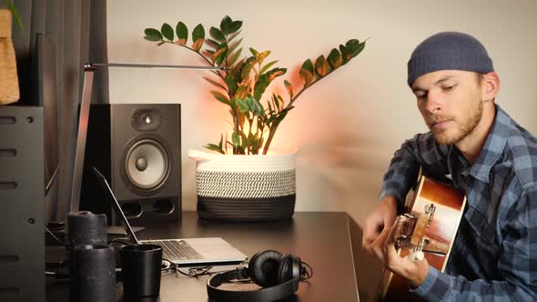 Guitarist tuning acoustic guitar, twisting guitar tuner pegs. alt