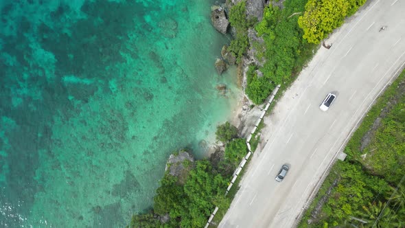 The Drone Descends to the Road That Runs Along the Seashore on a Tropical Island in the Philippines