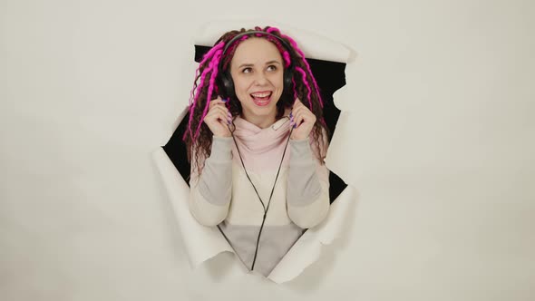 Young Woman in Headphones in Hole of White Background alt