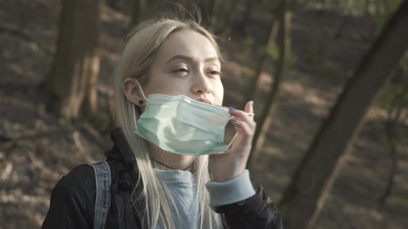 Close-up of Blond Girl with Hazel Eyes Taking Off Face Mask and Smiling. Portrait of Young Beautiful alt
