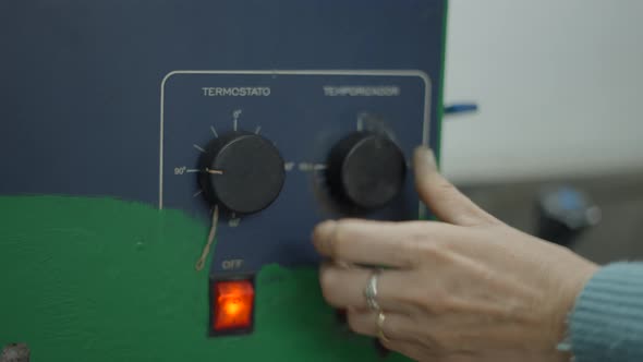 Female Hand Adjusting Temperature Knob Of A Jewelry Making Equipment At Workshop alt