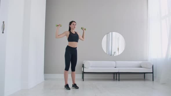 Raise the Dumbbells Over Your Head Performing Exercises for the Shoulders. Training at Home alt