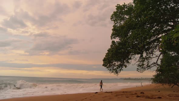 Young Man Walking on a Virgin Tropical Beach at Sunset