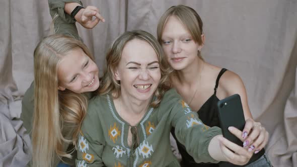 Close Up of Smiling Mother with Daughters Makes Funny Selfies on the Smartphone Grimacing alt