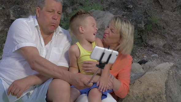 Grandparents and Grandchild Making Funny Mobile Selfie alt