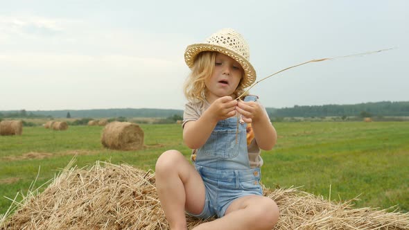 Funny Child Sitting on Haystack on Farmer Field. Farmer Daughter Walking in Field