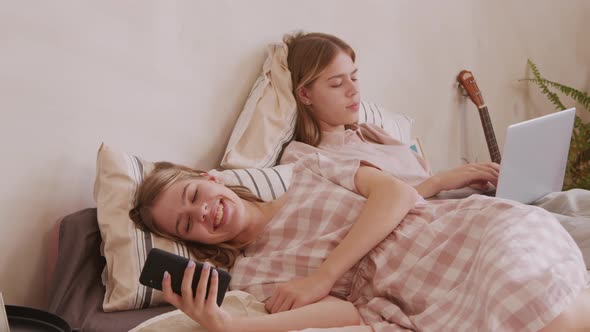 Twin Girls Lying on Bed and Using Gadgets alt