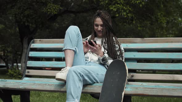 Cool skater girl texting outdoors. alt
