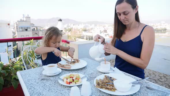 Family are Having a Breakfast Together on Terrace with Beautiful Mountains View