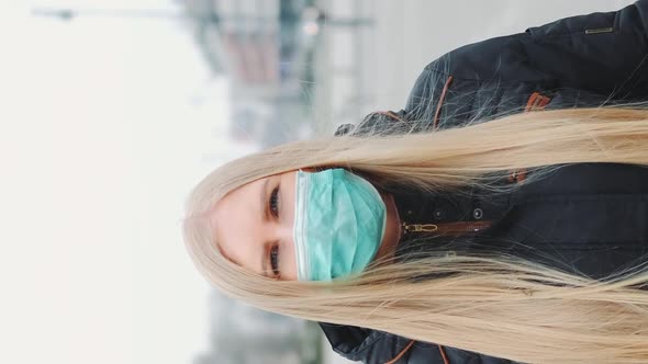 Coronavirus Pandemic Blonde Woman in a Medical Mask Walking Down the Street alt