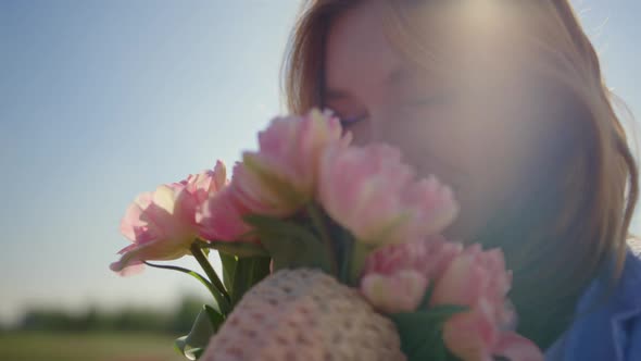 Portrait of Beautiful Woman Smelling Gentle Flower Bouquet in Sun Reflection alt