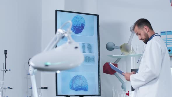 Dolly Shot of a Scientist in Modern Research Center Looking at Big TV alt