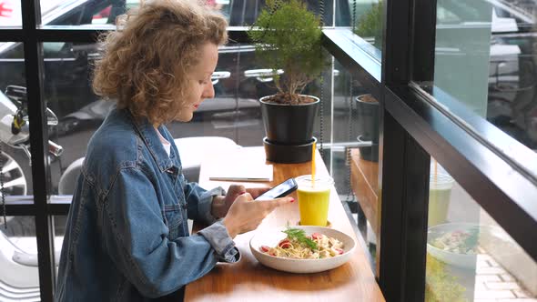 Young Fashionable Woman Using Smartphone On Lunch At Healthy Bistro alt