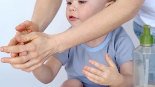 Mom and Son Washing Hands with a Disinfectant To Prevent Infection. alt