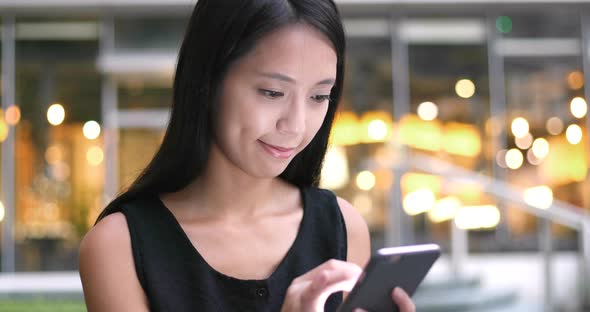 Woman Using cellphone with the background of Hong Kong city  alt