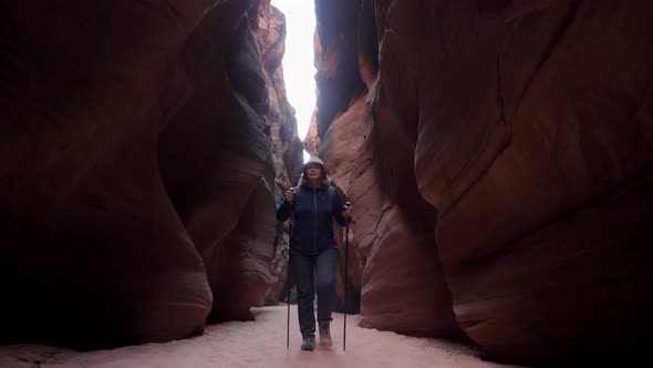 Hiker Walking On Dry Curve Riverbed In Deep Slot Canyon With Red Smooth Rocks alt