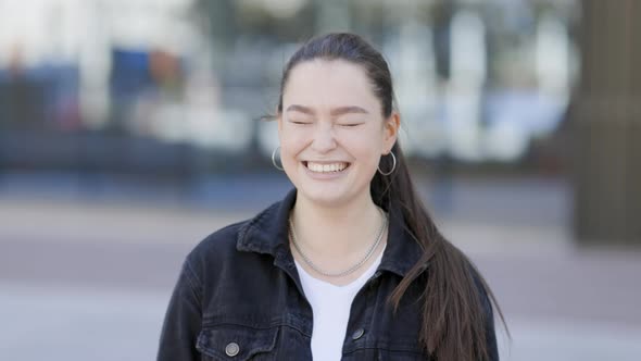 Dark-haired young woman looking at camera, laughing alt