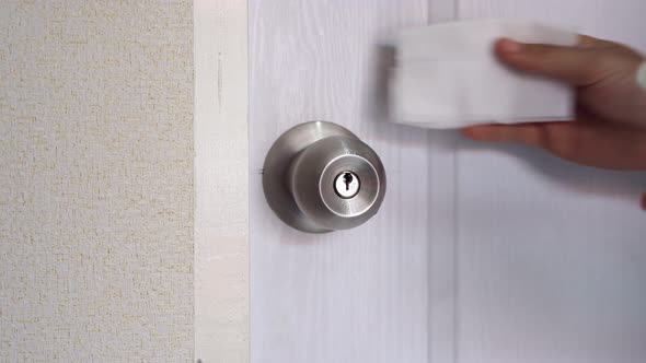 Young woman using alcohol spray for cleaning door knob to avoid infections corona virus and bacteria
