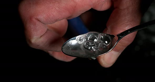 Drug, Cocaine in spoon against black background, Slow motion 4K alt