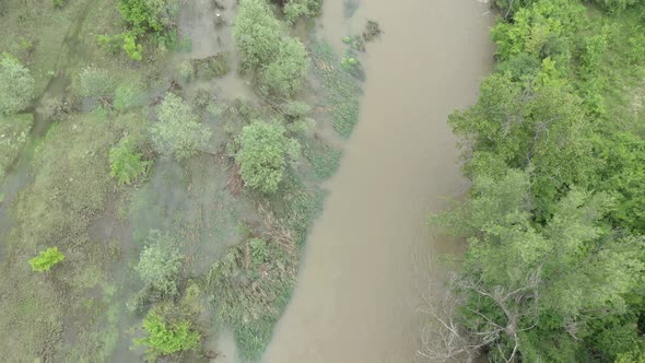 Flooding affects coastal area of narrow river 4K aerial footage alt