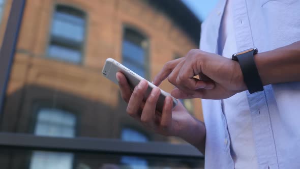 SMS, Text Messaging on Smartphone, Standing Young Black Male Designer alt