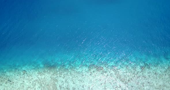 Luxury overhead island view of a white sandy paradise beach and blue sea background in colourful 4K alt