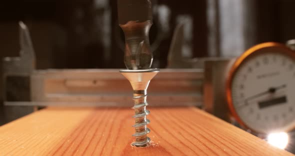Closeup is an Electric Drill the Screws a Selftapping Screw Into a Wooden Bar alt