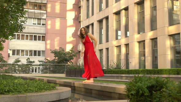 Beautiful Young Girl Dancing on the Street of a Modern City and Is Reflected in the Water alt