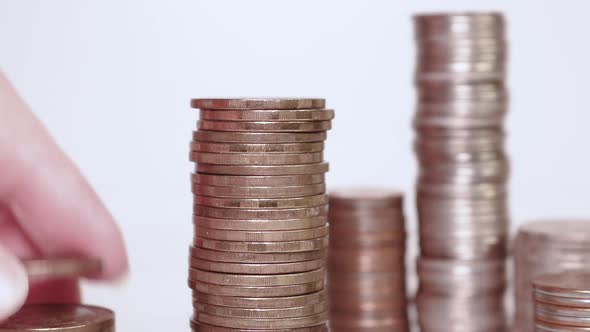 A woman's hand puts coins in a column. Investment concept. Metallic currency. Close-up action. alt