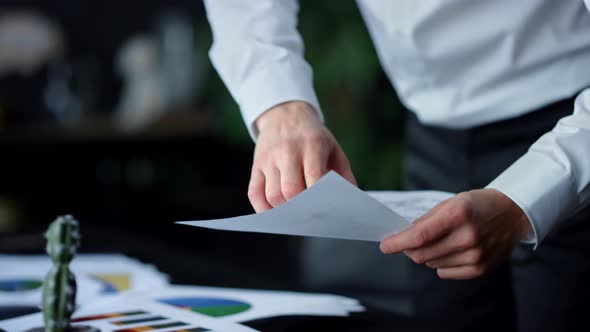 Unrecognizable Businessman Pointing in Document Indoors. Man Hands Holding Paper alt