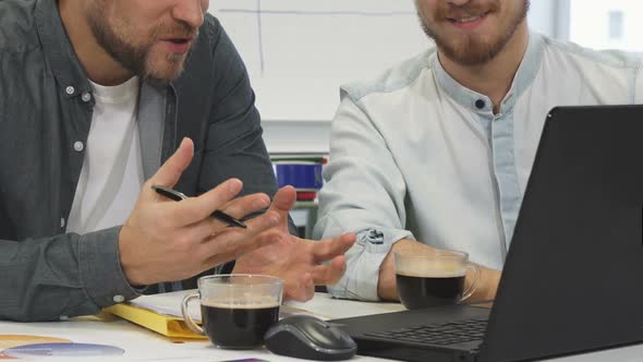 Cropped Shot of Two Male Business Colleagues Having Coffee Discussing Work