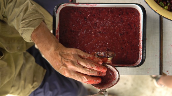 Man's hands chops summer berries for jam in grinder closeup alt