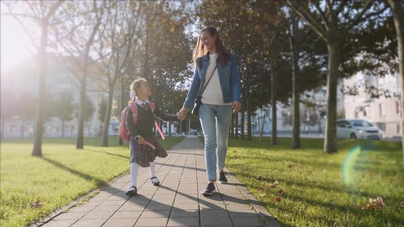 Young Woman and Daughter in School Uniform Walking in Sunny Weather Steadicam