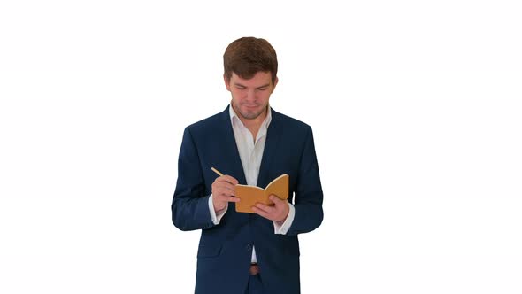 Young Businessman Thinking and Writing Notes in His Notebook While Walking on White Background