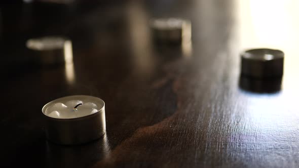 Blowing out many small tealight candle flames in slow motion with smoke flowing around after they ha alt