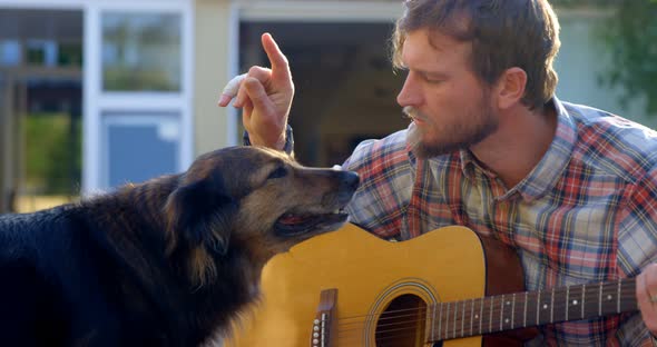 Man with his dog playing guitar in the garden 4k alt