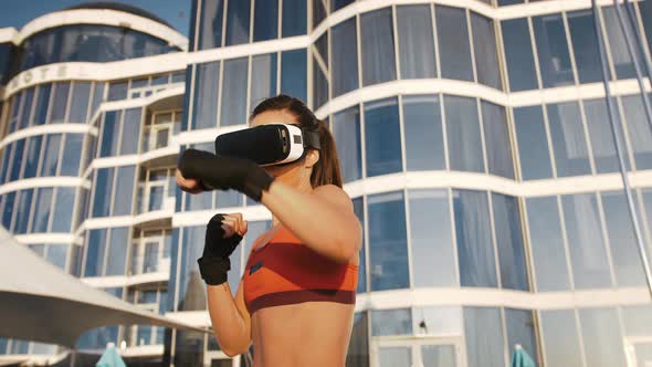 Young Female in VR Headset and Sportswear is Boxing By Hands Wrapped in Black Bandage Tape alt