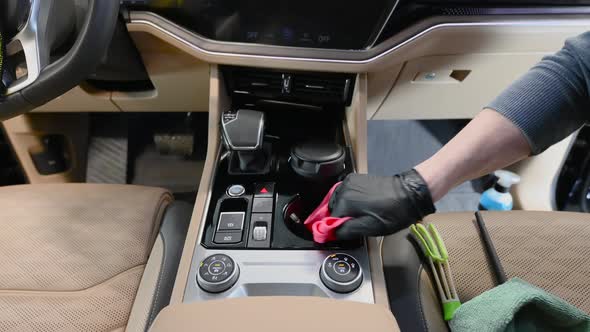 Male Worker Cleaning Car Interior with a Cloth Using a Detergent and Wiping Car's Central Dashboard alt