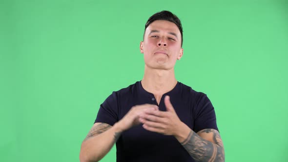 Portrait of Handsome Young Guy Is Looking Straight and Clapping Her Hands Indifferent. Burning alt