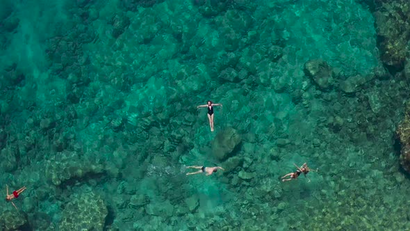 Aerial Top View of Young Woman in Black Bikini Is Swimming in the Turquoise Sea alt