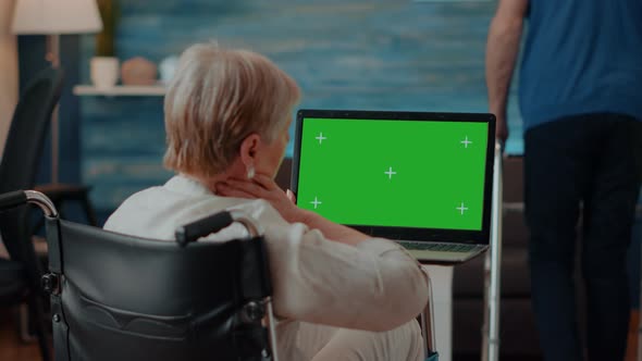 Old Person Holding Laptop with Green Screen Background alt