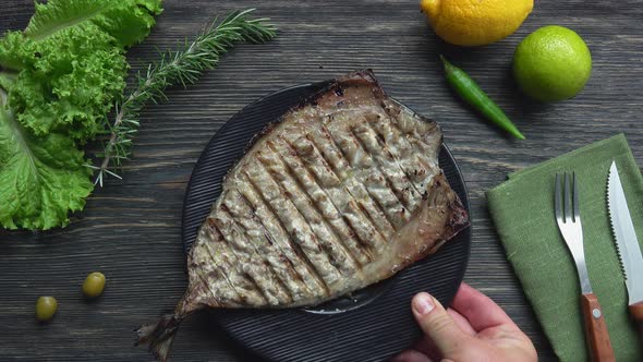 Top View of the Black Plate with Grilled White Mackerel Fish Placed on the Table alt