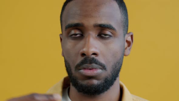 Closeup Portrait of Serious Young Man Pointing at Himself Then Making Zipping Mouth Gesture alt
