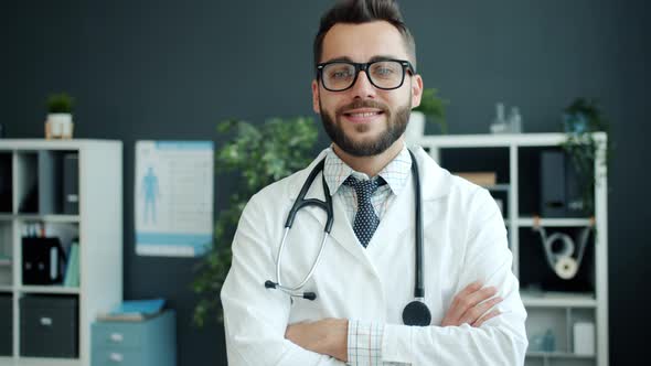 Portrait of Friendly Young Guy Doctor Smiling Standing in Office with Arms Crossed alt