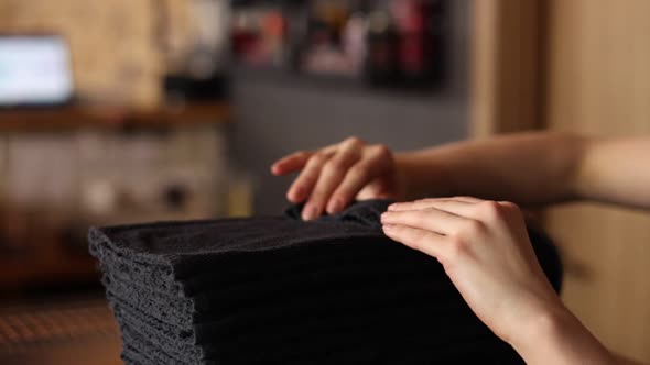 housewife woman touch a stack of fresh washed clean linen with her hands. black towels. homework.