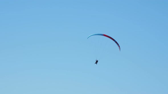 Tourist with Instructor Hovering in the Sky on a Paraglider. Tourist Attraction Over Rose Peak Cable alt